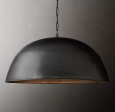 an industrial style pendant light hanging from a chain on a gray wall in a room