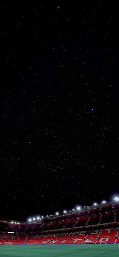 an empty soccer stadium at night with stars in the sky