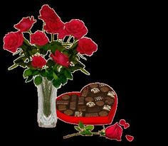 a vase filled with red roses and chocolates next to a heart shaped box