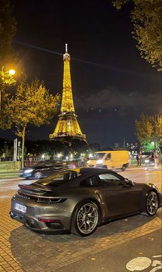 a black sports car parked in front of the eiffel tower, at night