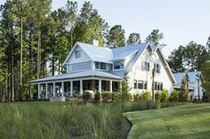 a large white house sitting in the middle of a lush green field next to trees