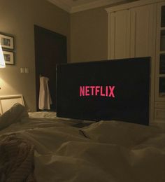 the netflix sign is lit up on top of an unmade bed in a bedroom