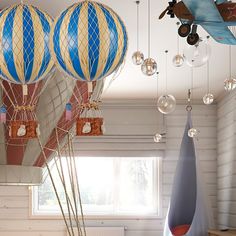 hot air balloons are hanging from the ceiling in a room with white walls and wood flooring