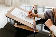 a woman is drawing on a piece of paper