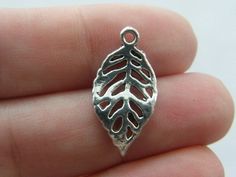 a small silver leaf charm on someone's finger