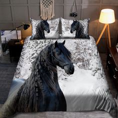 a black horse is standing in the snow on this bedding set with matching pillows