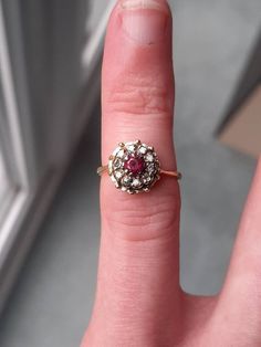 A vintage 18ct gold ruby and diamond ring. The ring is not Hallmarked but it has been tested as 1ct gold. The 3 x 3mm round cut ruby is claw set at the centre of the ring. This is surrounded by 10 round brilliant cut diamonds. The total diamond weight is 0.20ct's, and in our opinion the colour of the diamonds is an H/I, with a SI1 clarity. Finger size H, but we can make this ring bigger, or smaller. Vintage Red Ruby Ring With Halo Setting, Red Diamond Ring With Rose Cut Diamonds, Vintage Ruby Rings With Halo Setting, Vintage Ruby Cluster Ring With Center Stone, Red Ruby Ring With Single Cut Diamonds, Vintage Ruby Ring With Prong Setting And Diamond, Vintage Ruby Ring With Halo Setting And Round Cut, Vintage Red Diamond Birthstone Ring, Vintage Ruby Rings With Single Cut Diamonds