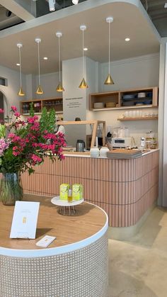 a table with flowers in a vase on top of it and an open counter behind it