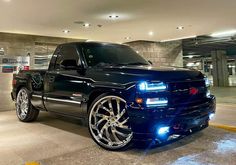 a black truck with chrome rims parked in a parking garage