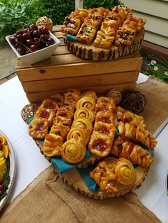 many pastries are on display in front of other foods and desserts at an outdoor gathering