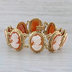 "Gemstone Information: - Natural Shell - Size - 13.5 x 10.5 mm Cut - Oval Carved Shell Color - Orange & White Metal: 18k Yellow Gold Weight: 23.3 Grams  Stamps: 750 Style: Oval Links Closure: Snap & Latch Inner Circumference: 6 3/4\" Width: 18.2 mm Each piece is thoroughly examined and refinished as needed by our professional jewelers, graded by our in-house GIA (Gemological Institute of America) Graduate Gemologist, and inspected for quality before being carefully packaged and promptly shipped. [SKU: A6594] phd" Luxury Yellow Gold Cabochon Bracelets, Luxury Yellow Gold Bracelets With Cabochon, Formal Yellow Gold Cabochon Jewelry, Yellow Gold Intaglio Bracelet For Formal Occasions, Antique Polished Bracelets For Formal Occasions, Formal Yellow Gold Intaglio Bracelets, Formal Yellow Gold Intaglio Bracelet, Collectible Yellow Gold Bracelets, Elegant Yellow Gold Collectible Bracelets