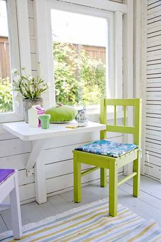 a green chair sitting in front of a window next to a table with a potted plant on it