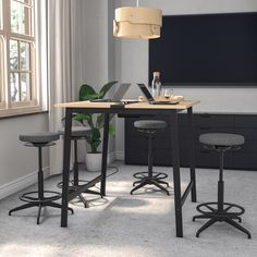 a table with two stools and a laptop on it in front of a window