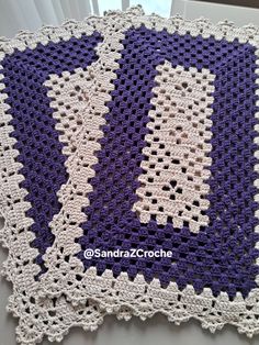 a purple and white crocheted afghan on a window sill