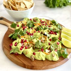 a wooden cutting board topped with guacamole and chips