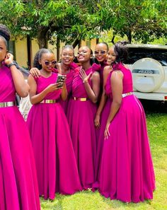 a group of women in pink dresses standing next to each other and taking pictures with their cell phones