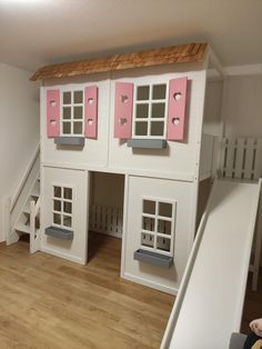 a child's play house with stairs and pink windows on the top half of it