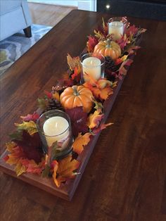 a wooden table topped with candles and fall leaves