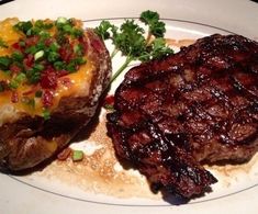 two steaks and potatoes on a white plate