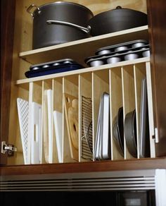 an open cabinet with pots and pans on the bottom shelf in front of it