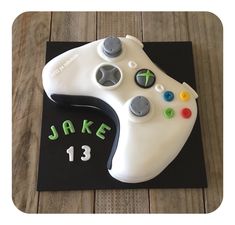 a cake shaped like a video game controller on top of a black board with the number thirteen printed on it