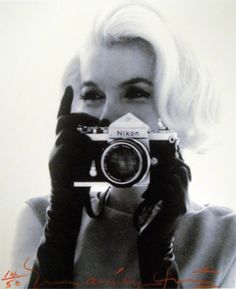 a woman holding up a camera in front of her face with the words nikon on it