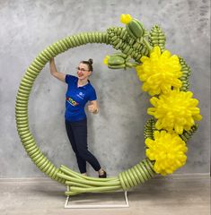 a woman is standing in front of a sculpture made out of bananas and yellow flowers