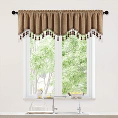 a kitchen window curtain with tassels hanging from it's valance, in front of a sink