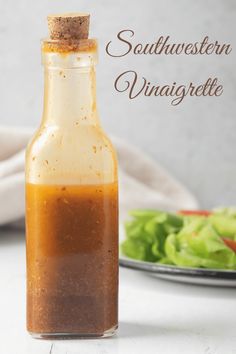 a bottle filled with dressing next to a plate of lettuce