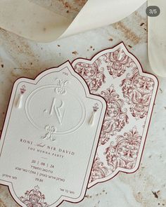 two red and white wedding cards on a marble surface