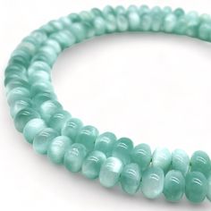 a strand of light green glass beads on a white background