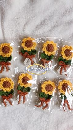 six crocheted sunflowers in plastic bags on a white blanket with the words hola crochet