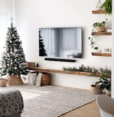 a living room with a christmas tree in the corner and a flat screen tv on the wall