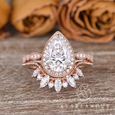 an engagement ring set with a pear shaped diamond surrounded by small white and rose cut diamonds