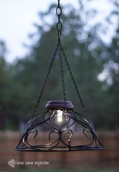 a light hanging from a chain in the middle of a yard with trees in the background