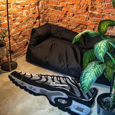 a room with a brick wall and plants on the floor next to an air mattress