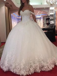 a woman in a white wedding dress is standing on a red carpet and posing for the camera