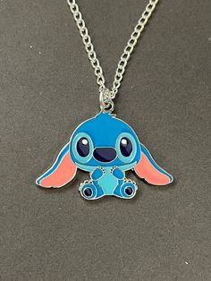 a blue and pink necklace with a small cartoon character on it's front end