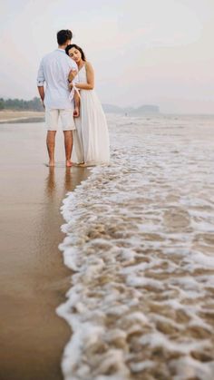 a man and woman are standing in the water at the beach with their arms around each other