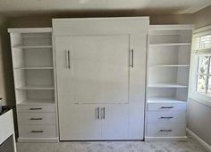 an empty room with white cupboards and carpeted flooring in the middle of it