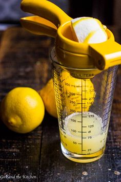 a measuring cup filled with lemons on top of a wooden table