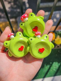 there are three green frog figurines with red hearts on their mouths and eyes