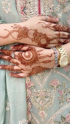 two hands with henna on them are holding each other's hand and wearing bracelets