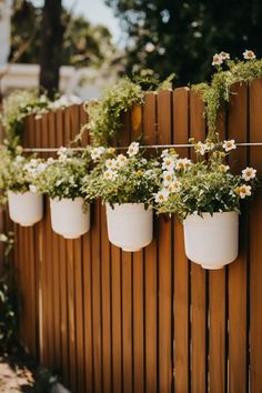 some white flowers are hanging from a wooden fence