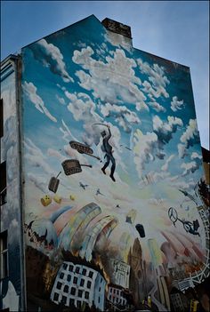 a large mural on the side of a building with people flying kites in the sky