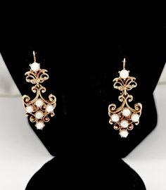 Vintage Victorian style 14K solid gold drop dangle cultured Pearl earrings. Very pretty style and design. Each earring measures 1 1/2" long(top of hook to bottom pearl) x 5/8" wide and their combined weight is 8.1 grams. The cultured white pearls are all 4mm diameter. None are damaged or discolored and they show nice luster. The earrings have locking fish hook fasteners for pierced ears. Overall very good condition with modest wear. Stamped 14k along with unidentified MH maker's mark. Please enlarge all pics for best details. Victorian Style Drop Pearl Earrings, Victorian Style Formal Pearl Drop Earrings, White Pierced Chandelier Earrings For Formal Occasions, Formal White Pierced Chandelier Earrings, Ornate White Pearl Drop Earrings, Victorian Dangle Pearl Earrings, Ornate Pearl Drop Earrings For Formal Occasions, White Victorian Earrings For Formal Occasions, Victorian Style White Earrings For Formal Occasions