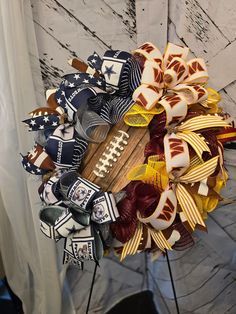 a wreath made out of football bows on a wooden board with an american flag design