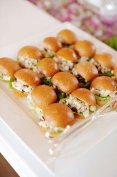 small sandwiches are arranged on a white plate