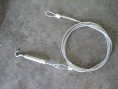 a white cord on the ground with a hook in it's center and two ends connected to each other