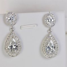 two pairs of diamond earrings on display in a white box with clipping for clips